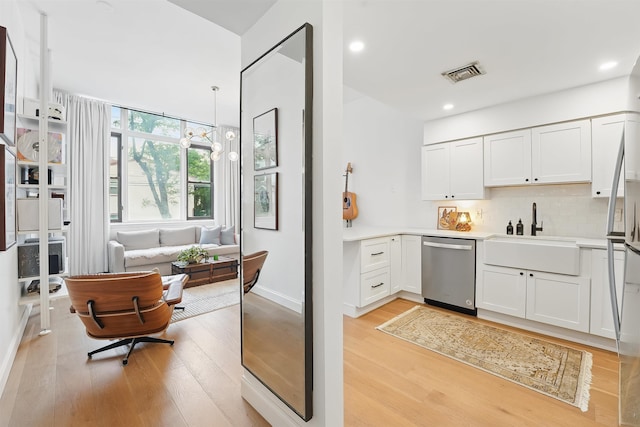 120 Sherman Ave Unit 2B, Jersey City, NJ 07307 - kitchen featuring stainless steel dishwasher, a sink, light wood-style floors, light countertops, and backsplash