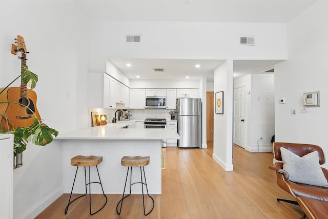 120 Sherman Ave Unit 2B, Jersey City, NJ 07307 - kitchen with stainless steel appliances, a peninsula, a kitchen bar, a sink, and light countertops