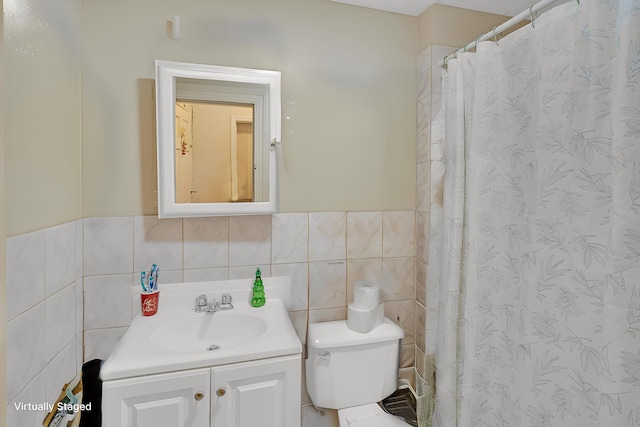 bathroom with vanity, toilet, and tile walls