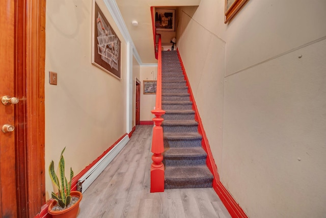 staircase with wood-type flooring and a baseboard heating unit