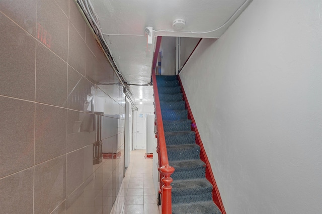 stairs featuring tile walls