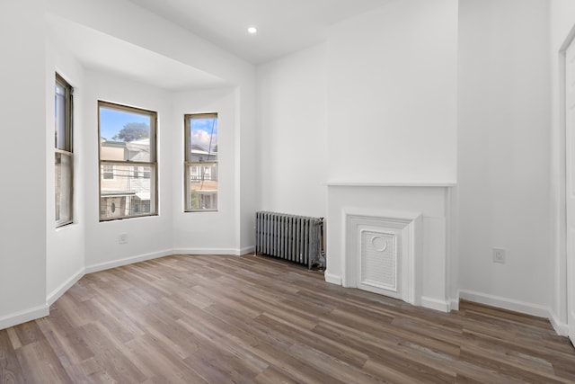 unfurnished living room featuring radiator and wood-type flooring