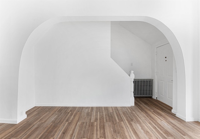 interior space with radiator heating unit, hardwood / wood-style floors, and vaulted ceiling