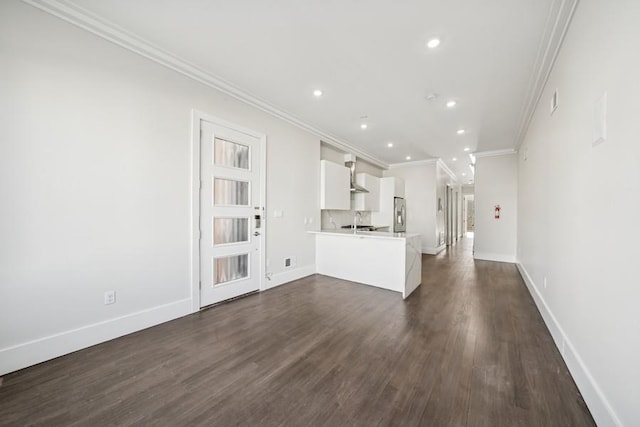 unfurnished living room featuring a sink, dark wood finished floors, recessed lighting, baseboards, and ornamental molding