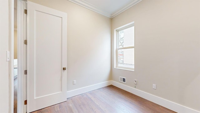 empty room with baseboards, ornamental molding, visible vents, and light wood-type flooring
