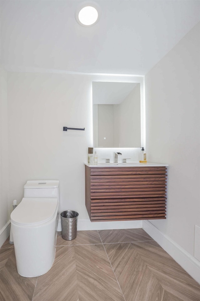 bathroom featuring vanity, parquet flooring, and toilet