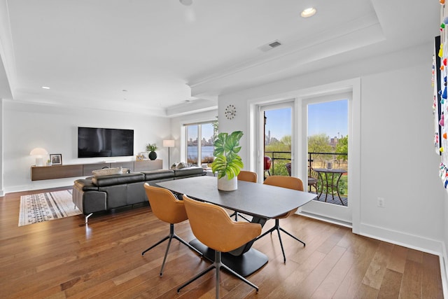 dining room with hardwood / wood-style flooring, recessed lighting, visible vents, baseboards, and a raised ceiling