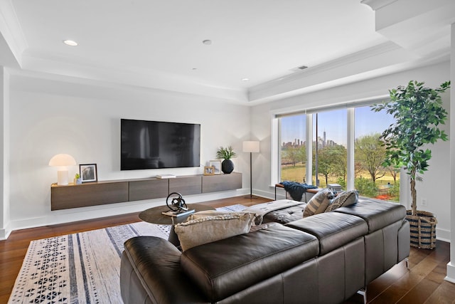 living room featuring a tray ceiling, wood finished floors, and baseboards