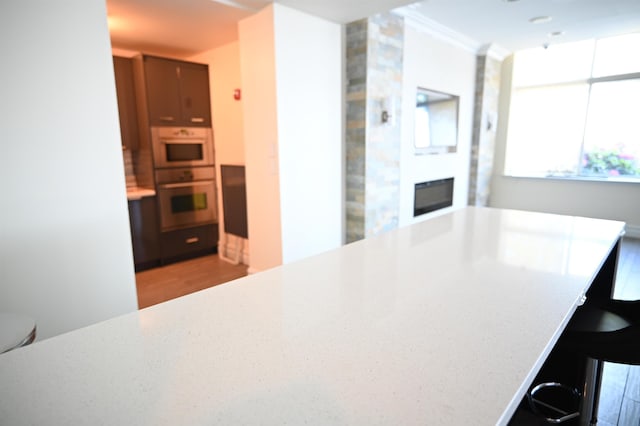 20 2nd St Unit 2111, Jersey City, NJ 07034 - kitchen featuring double oven, a glass covered fireplace, light countertops, a kitchen breakfast bar, and crown molding