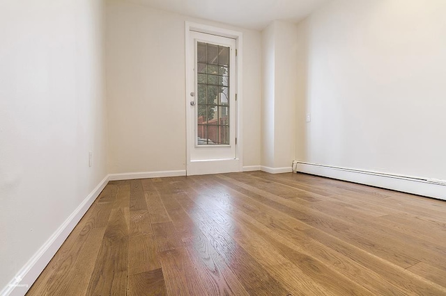 72 W 22nd St, Bayonne, NJ 07002 - spare room featuring wood finished floors, baseboards, and a baseboard radiator