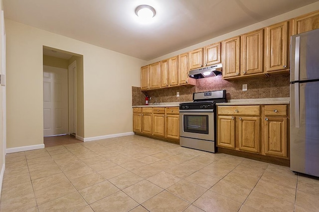 72 W 22nd St, Bayonne, NJ 07002 - kitchen with appliances with stainless steel finishes, under cabinet range hood, decorative backsplash, light tile patterned flooring, and baseboards