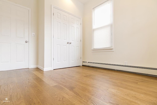 72 W 22nd St, Bayonne, NJ 07002 - unfurnished bedroom featuring a baseboard radiator, wood finished floors, a closet, and baseboards