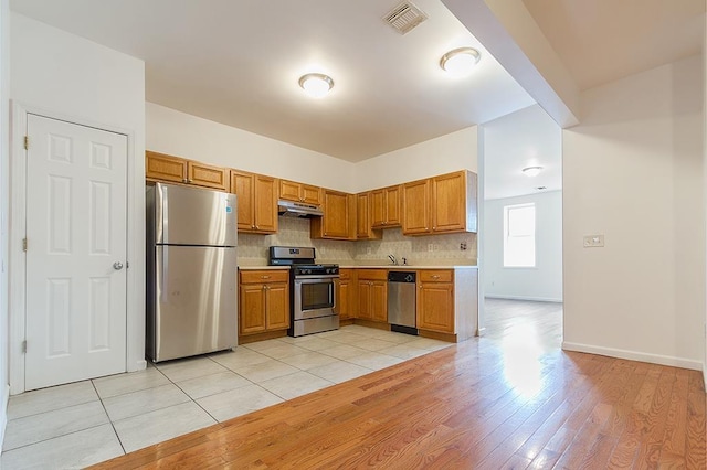 kitchen featuring light wood-type flooring, appliances with stainless steel finishes, sink, and tasteful backsplash