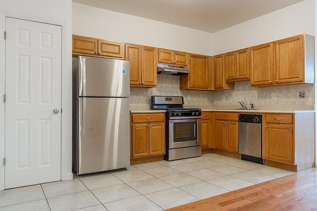 kitchen with light tile patterned floors, sink, stainless steel appliances, and backsplash