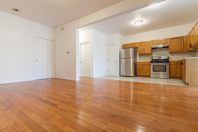 kitchen with backsplash, stainless steel appliances, and light hardwood / wood-style floors