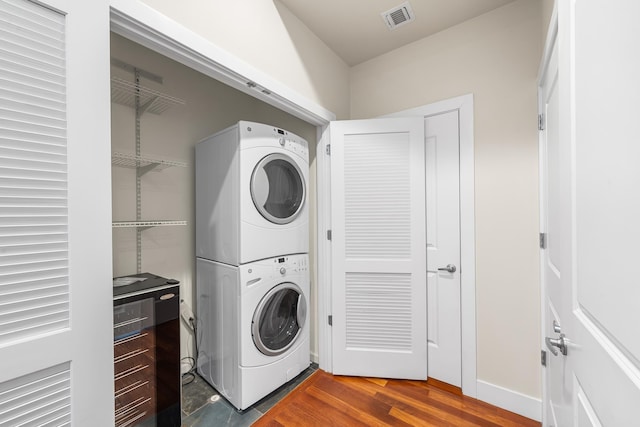 washroom featuring stacked washing machine and dryer and wood finished floors