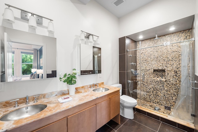 bathroom with a shower stall, tile patterned flooring, double vanity, and toilet