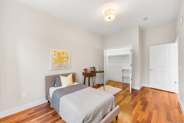 bedroom with baseboards, light wood-style floors, and a closet