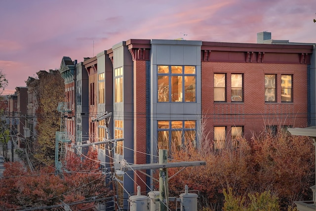 property exterior at dusk featuring brick siding and fence