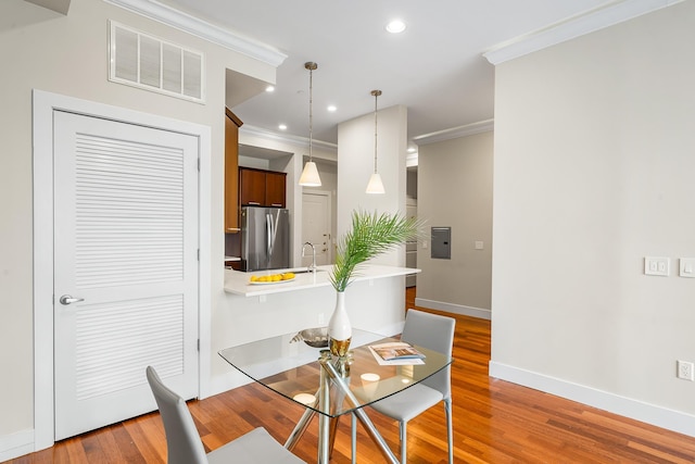 dining space featuring baseboards, crown molding, wood finished floors, recessed lighting, and electric panel