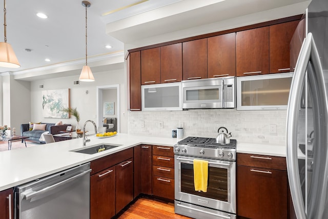 kitchen with appliances with stainless steel finishes, a sink, light countertops, recessed lighting, and ornamental molding