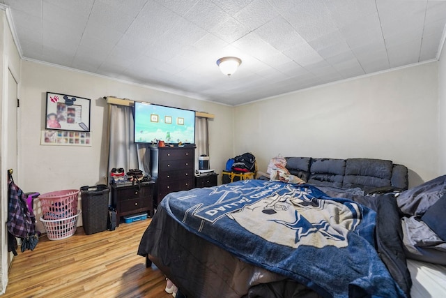 bedroom with wood finished floors and crown molding