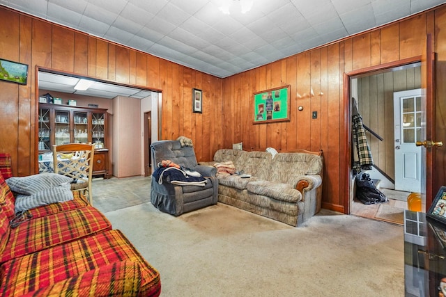 carpeted living room with wood walls