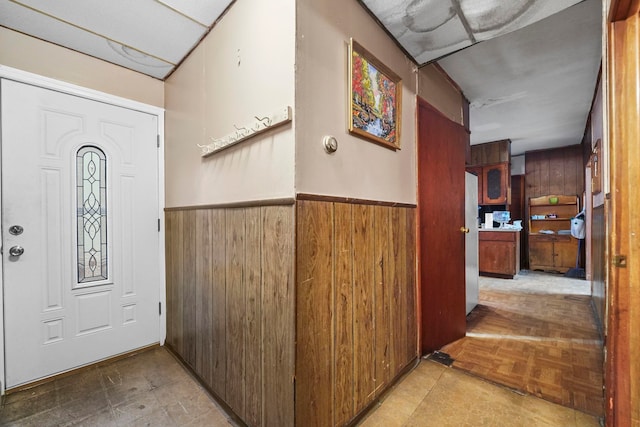 entrance foyer featuring wainscoting, tile patterned floors, and wooden walls