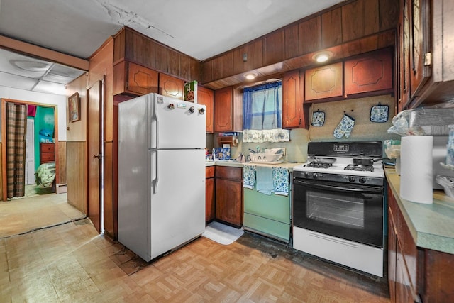 kitchen featuring light countertops, baseboard heating, freestanding refrigerator, light floors, and gas range oven