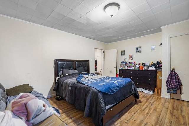 bedroom featuring ornamental molding and wood finished floors