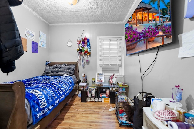 bedroom featuring ornamental molding and wood finished floors