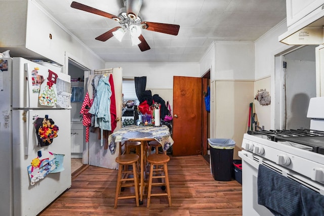 kitchen with crown molding, a ceiling fan, wood finished floors, white appliances, and under cabinet range hood