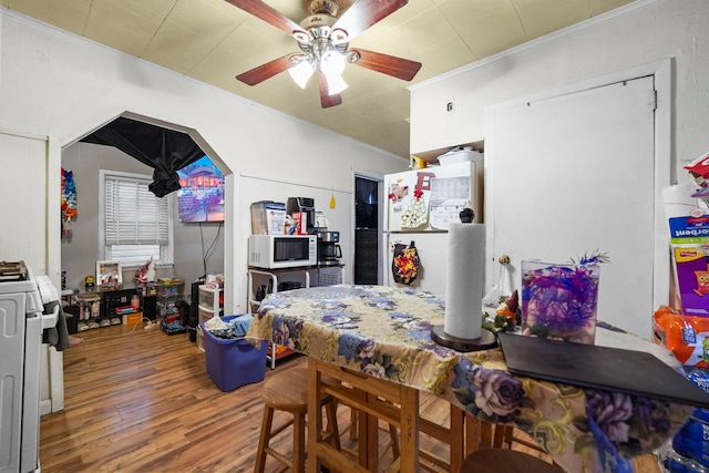 dining space featuring a ceiling fan, crown molding, and wood finished floors