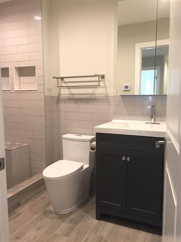 bathroom with hardwood / wood-style floors, vanity, tile walls, and toilet