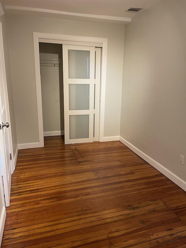 unfurnished bedroom with dark hardwood / wood-style flooring and a closet