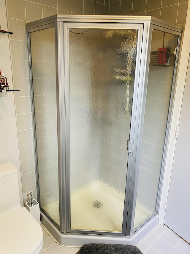 bathroom featuring tile patterned floors, a stall shower, and toilet