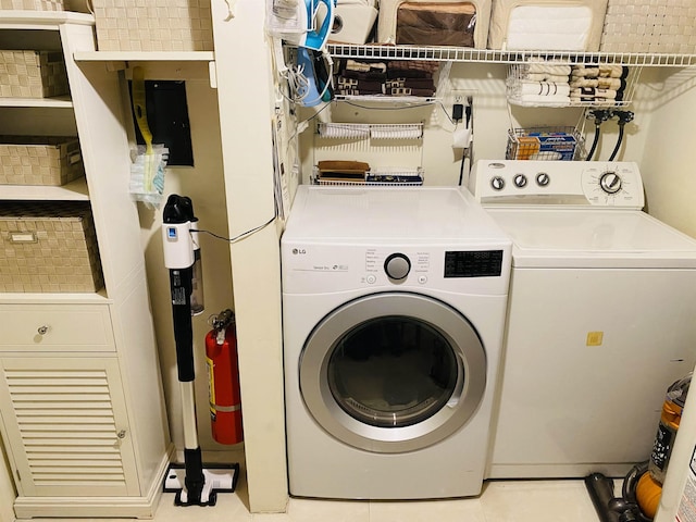 clothes washing area with laundry area, light tile patterned floors, and washer and clothes dryer