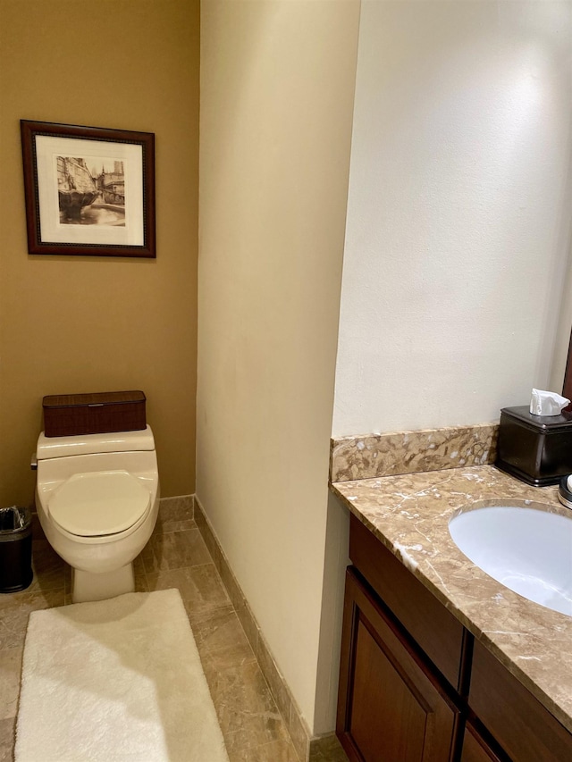 half bath featuring toilet, vanity, and baseboards