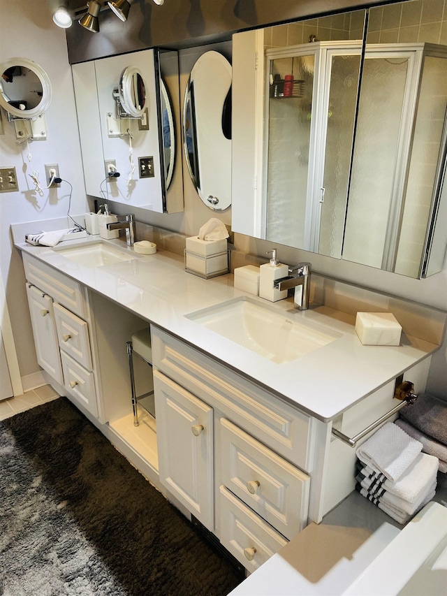 bathroom with double vanity, a stall shower, tile patterned floors, and a sink