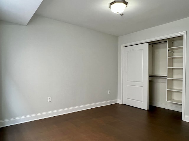 unfurnished bedroom featuring dark wood-type flooring and a closet