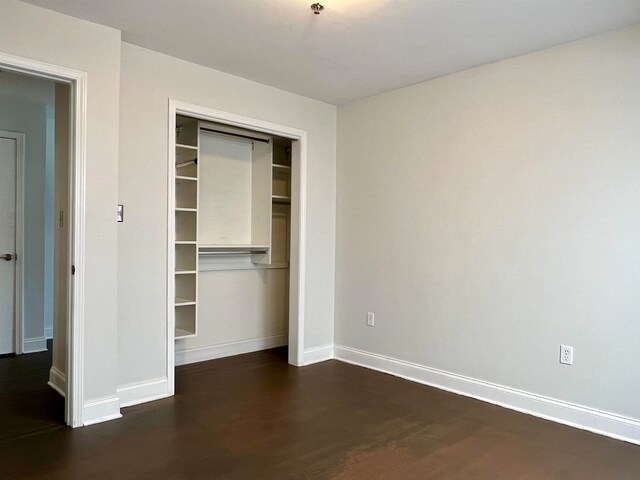 unfurnished bedroom with dark hardwood / wood-style floors and a closet