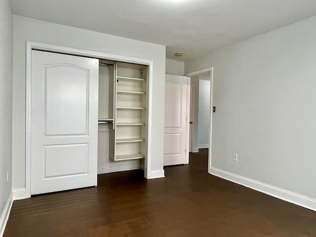 unfurnished bedroom featuring dark wood-type flooring and a closet