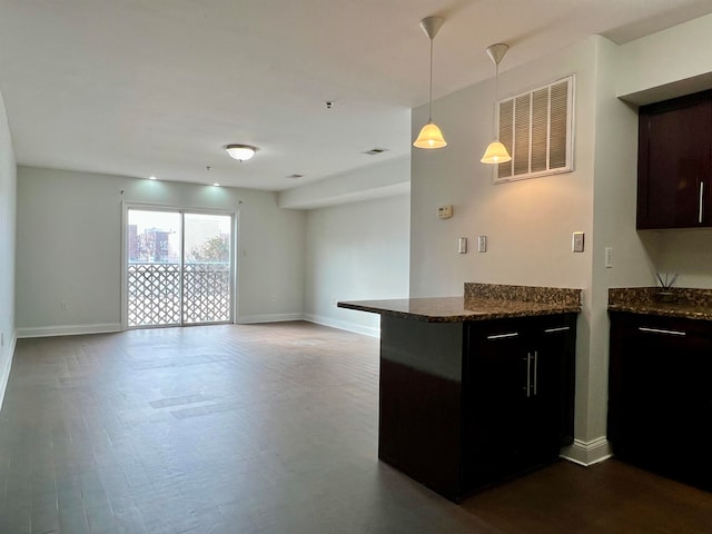 kitchen with hanging light fixtures, dark stone countertops, dark hardwood / wood-style floors, and kitchen peninsula