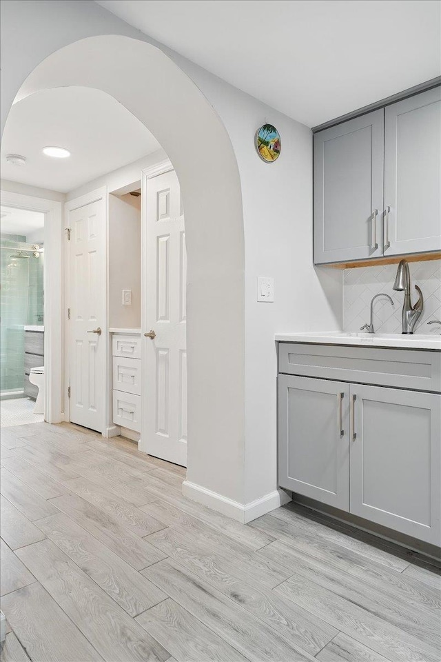 221 Terrace Ave, Jersey City, NJ 07307 - bar area featuring light wood-style floors, arched walkways, decorative backsplash, and a sink