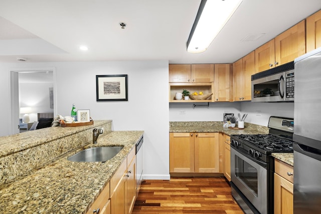 kitchen featuring visible vents, light stone counters, wood finished floors, stainless steel appliances, and a sink