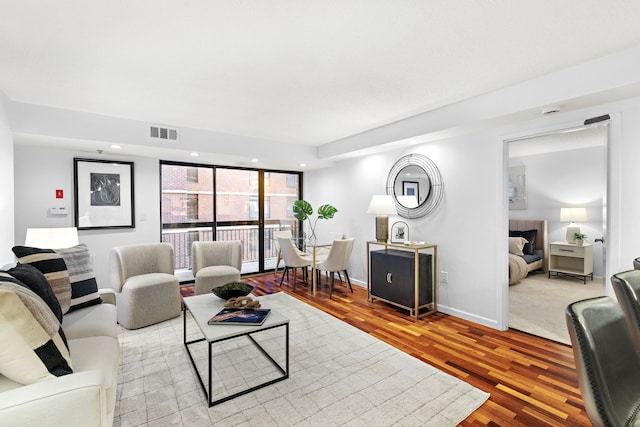 living room with recessed lighting, visible vents, baseboards, and wood finished floors