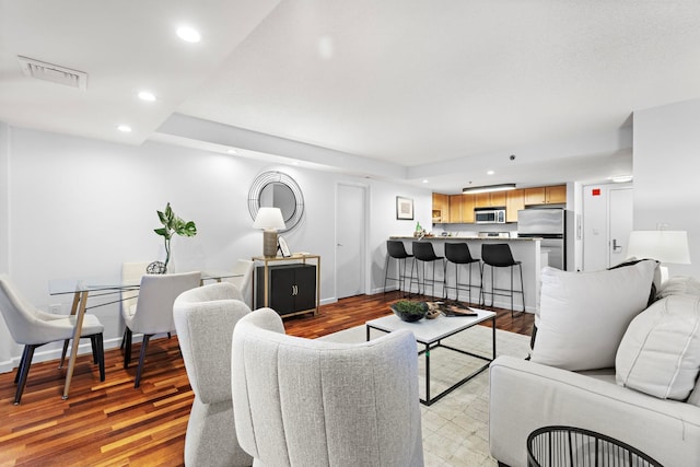 living room featuring light wood-style floors, recessed lighting, visible vents, and baseboards