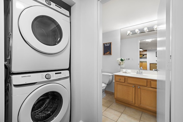 clothes washing area featuring laundry area, stacked washer and clothes dryer, a sink, and light tile patterned floors