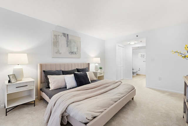 bedroom featuring a closet, baseboards, connected bathroom, and light colored carpet