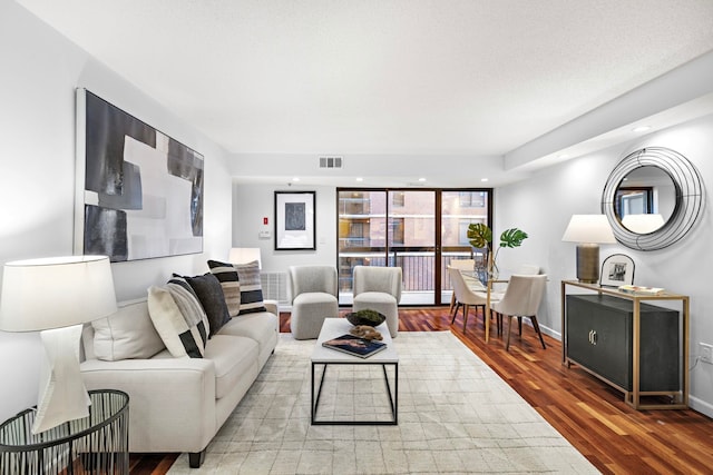 living area with recessed lighting, visible vents, baseboards, and wood finished floors